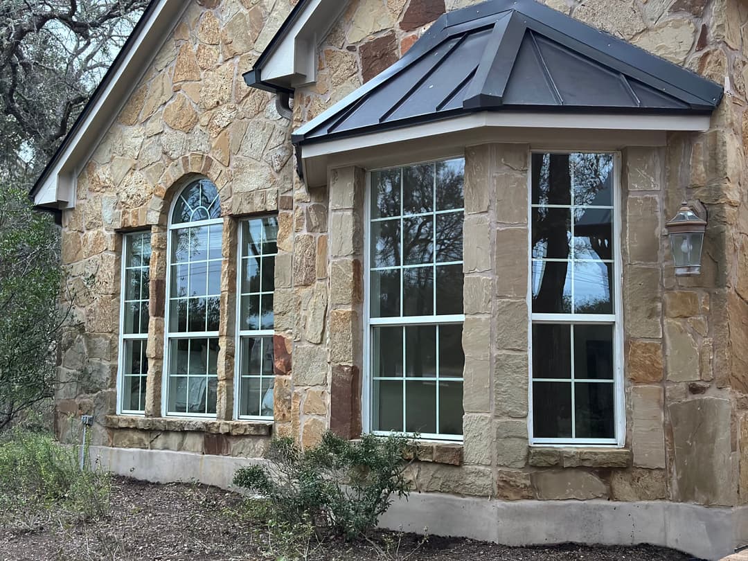 Stone house exterior featuring large windows and a distinctive roofline.