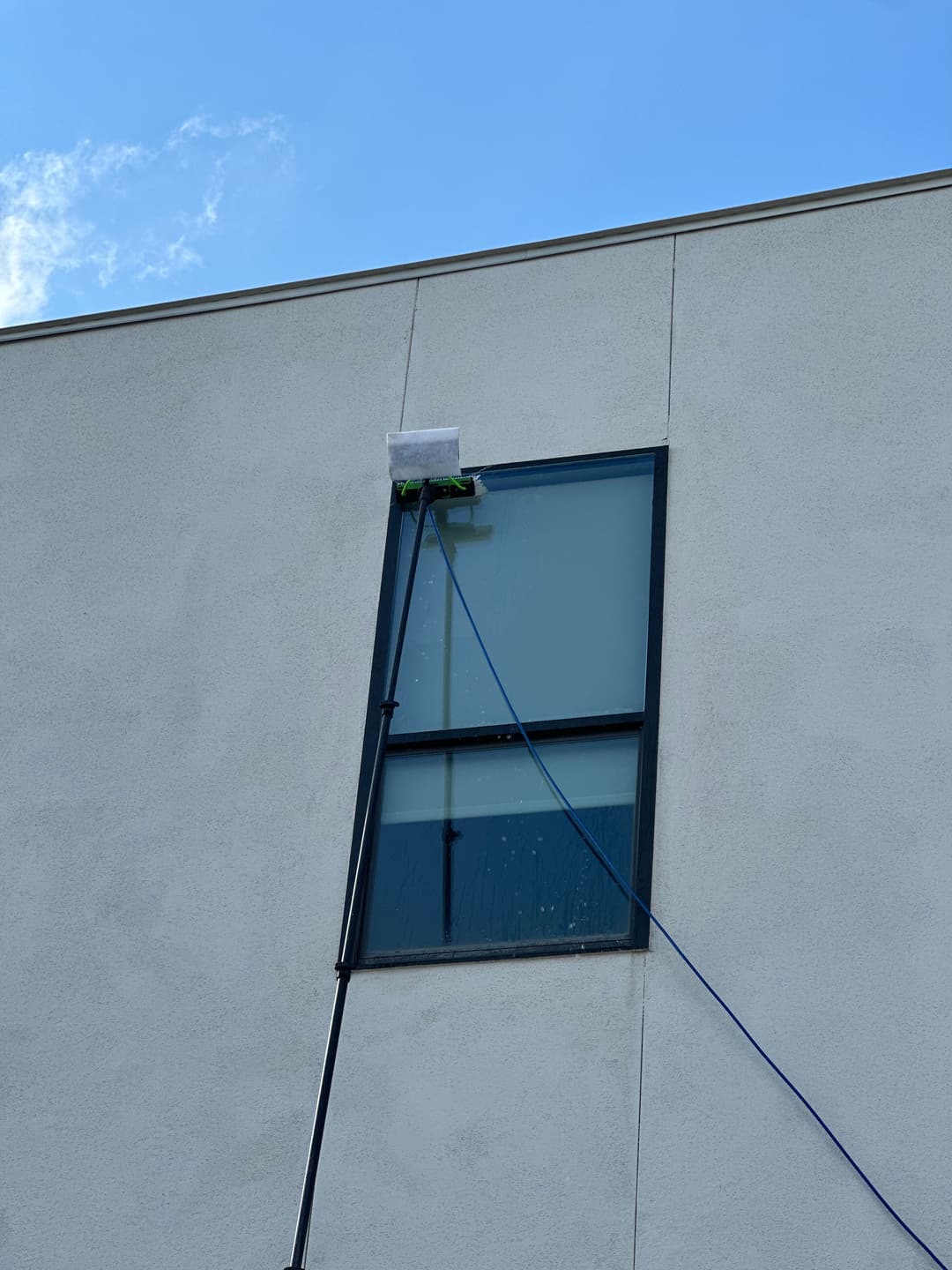 Window cleaning equipment on a high-rise building with blue sky backdrop.