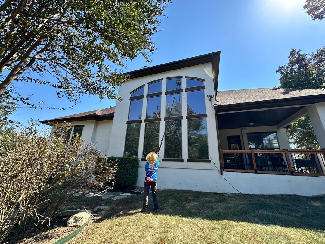Child admiring large windows of a modern home with patio on a sunny day.