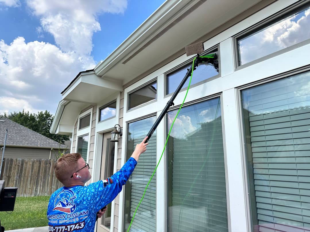 Professional window washing service in action, featuring a young man using a squeegee tool.