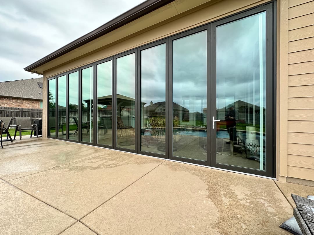 Modern glass sliding doors with backyard view and pool, enhancing outdoor connectivity.