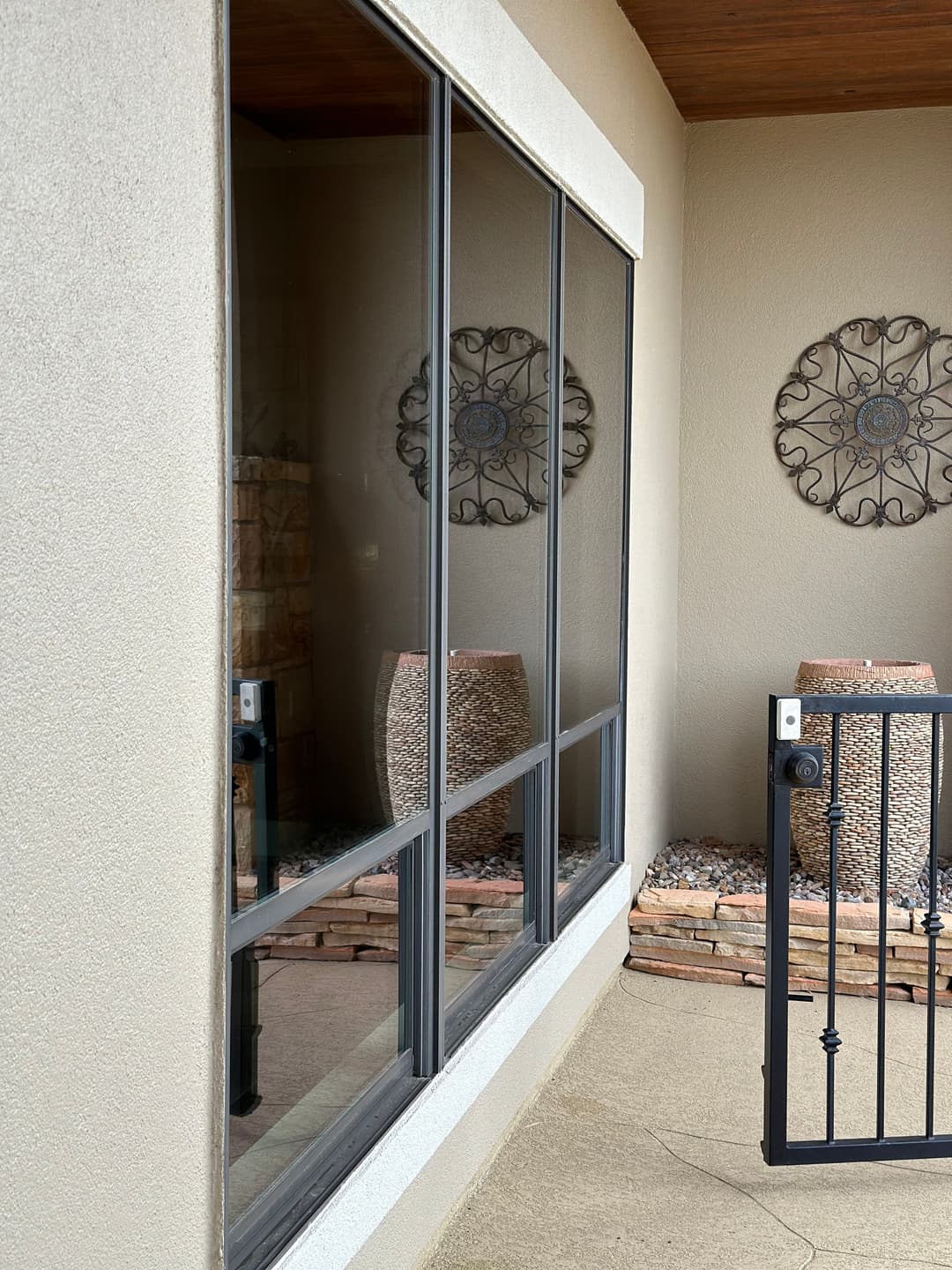 Modern exterior featuring large windows, decorative metal wall art, and stylish planters.