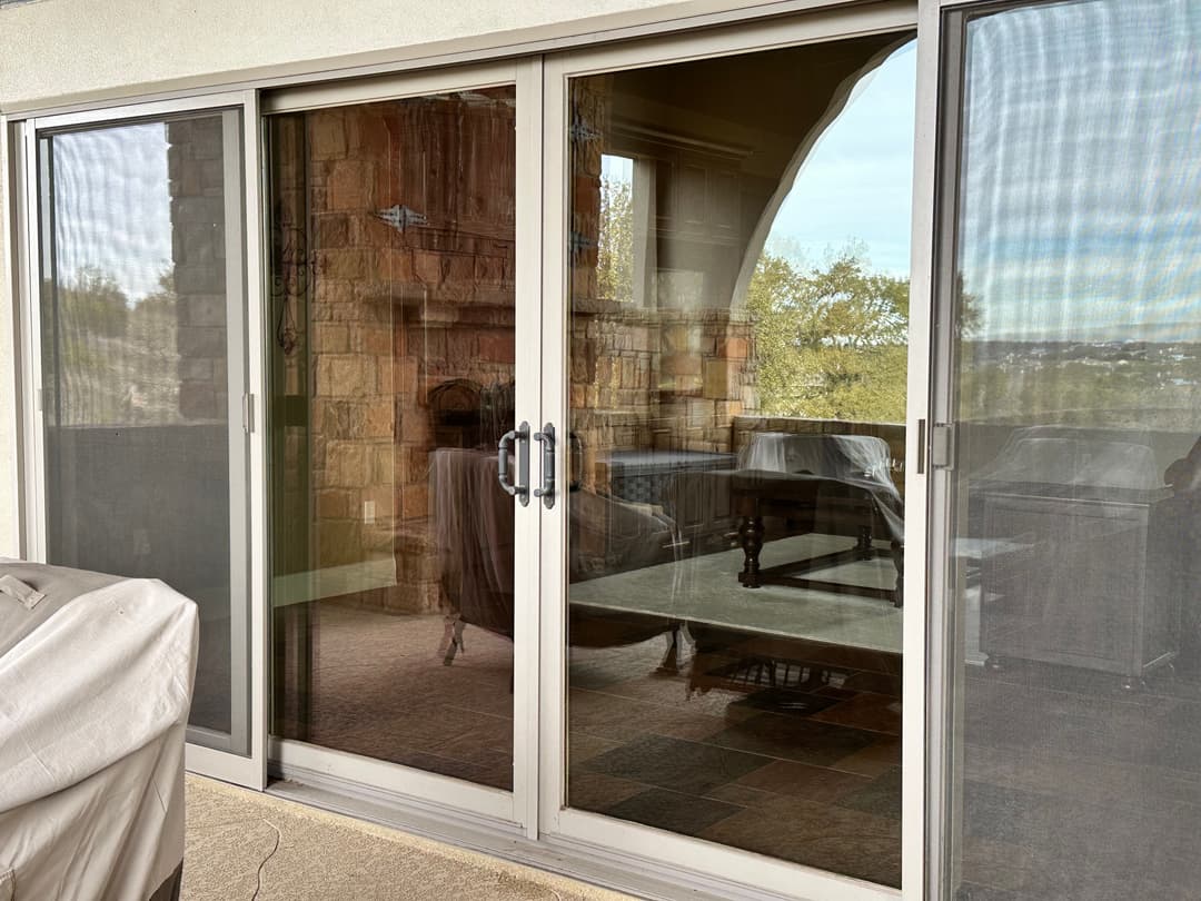 Sliding glass doors leading to a patio with a stone fireplace and outdoor seating area.