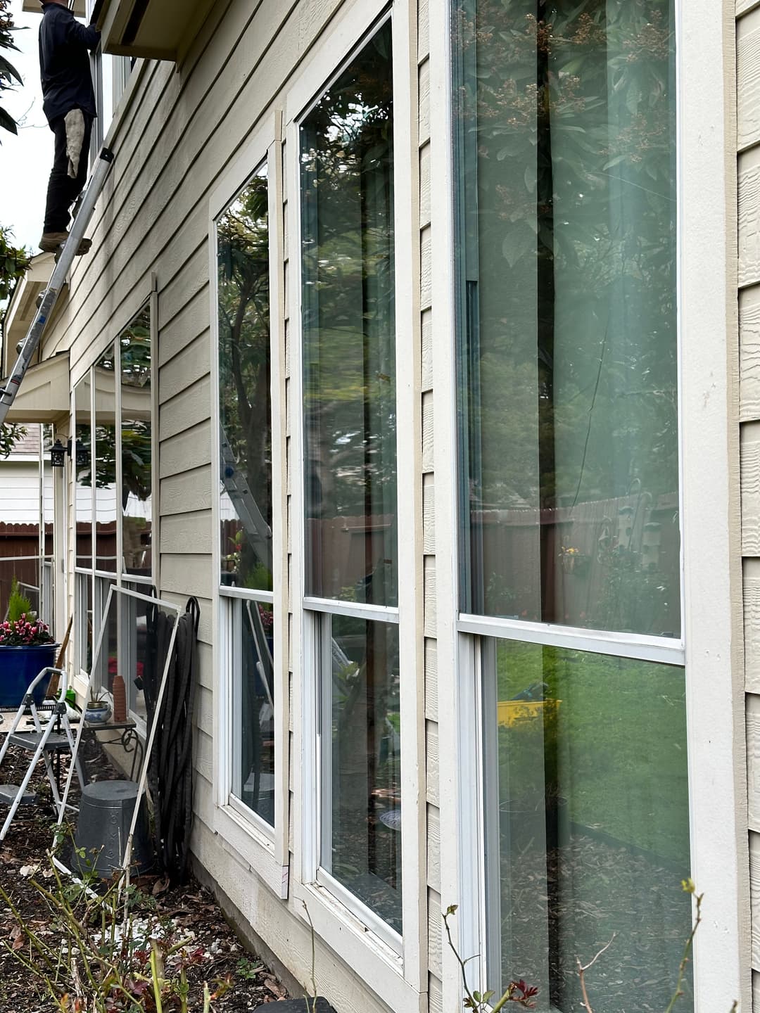 Person cleaning windows of a house, showcasing modern glass-pane design and exterior details.