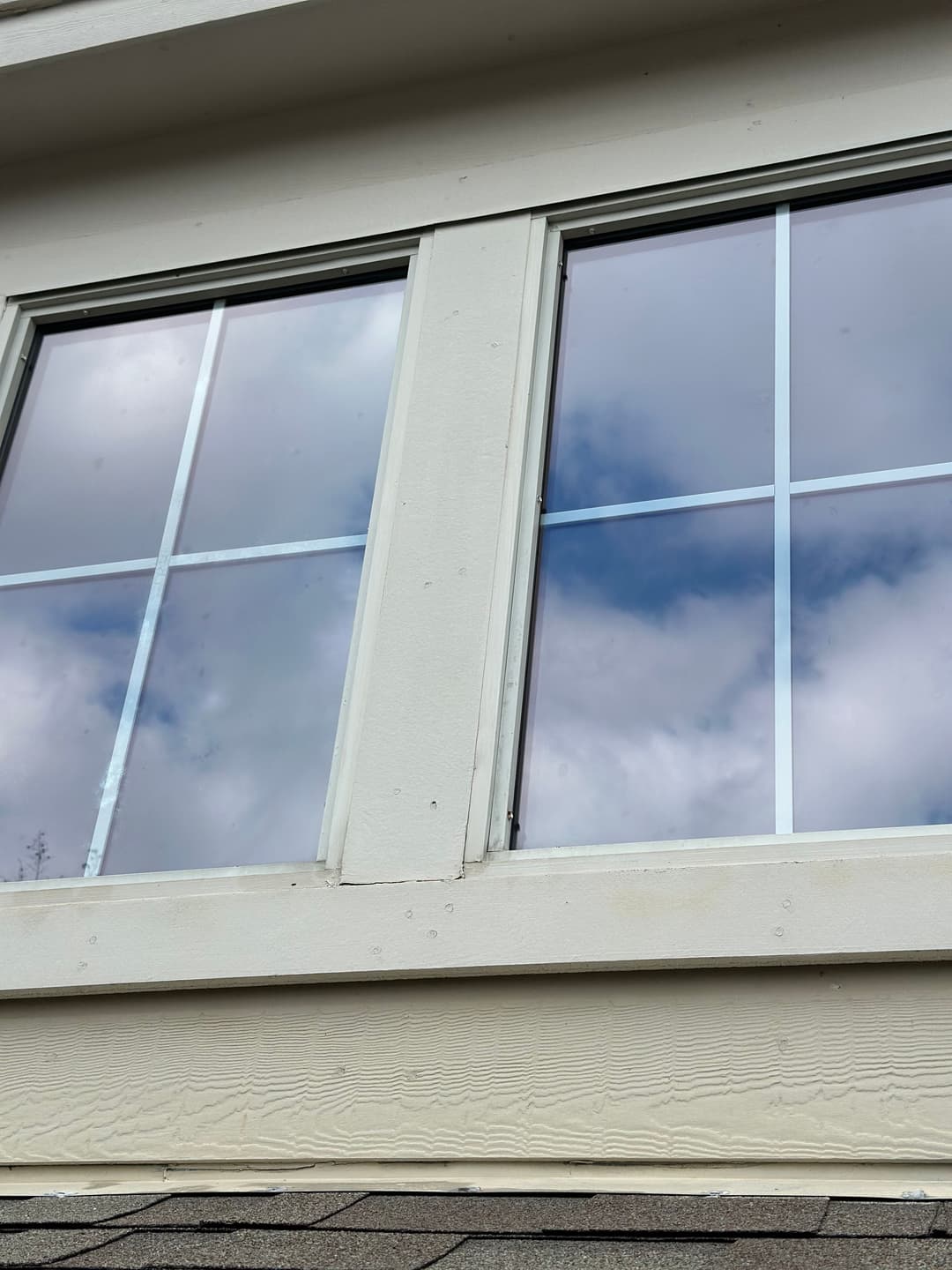 Two windows on a house reflecting clouds and the sky, showcasing modern architecture.
