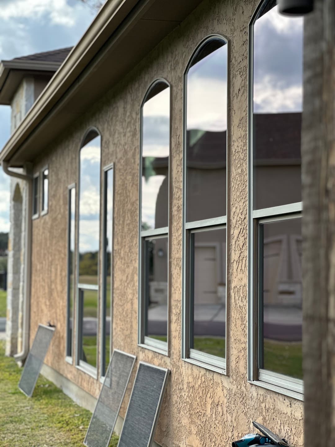 Modern building exterior featuring large arched windows and a textured wall finish.