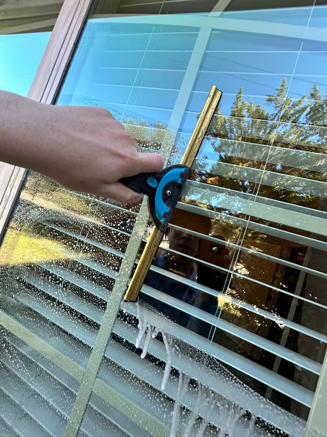 Person cleaning window with a squeegee, showing effective window cleaning technique.