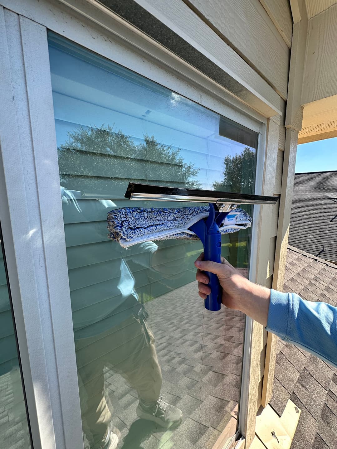 Person cleaning window with squeegee, showcasing home maintenance and window care tips.
