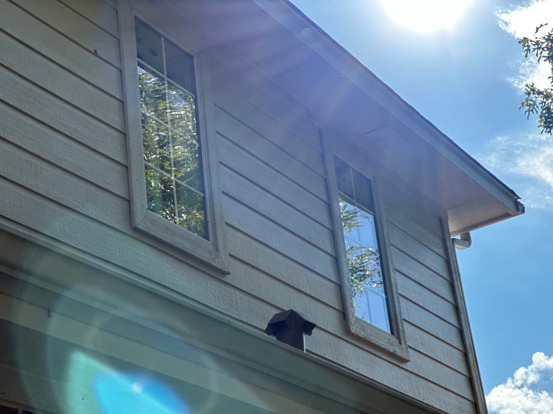 Sunlight reflecting off windows of a modern home under a clear blue sky.