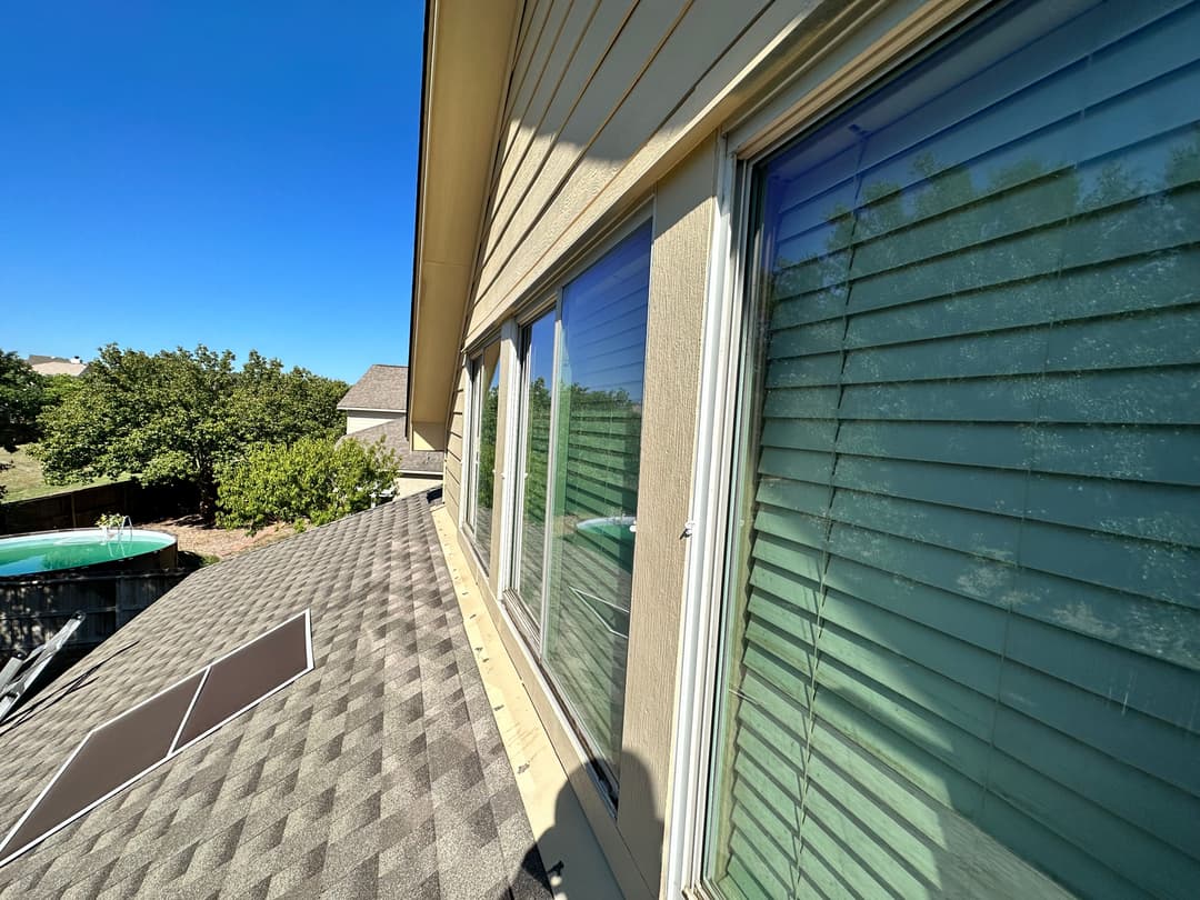 View of residential windows on a sloped roof under a clear blue sky.