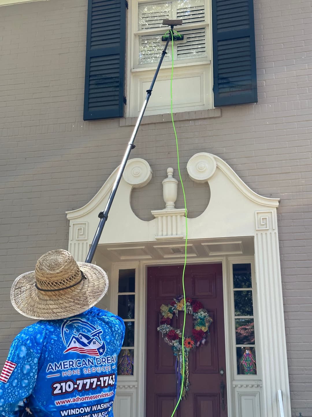 Professional window cleaning service using extendable pole for hard-to-reach windows.