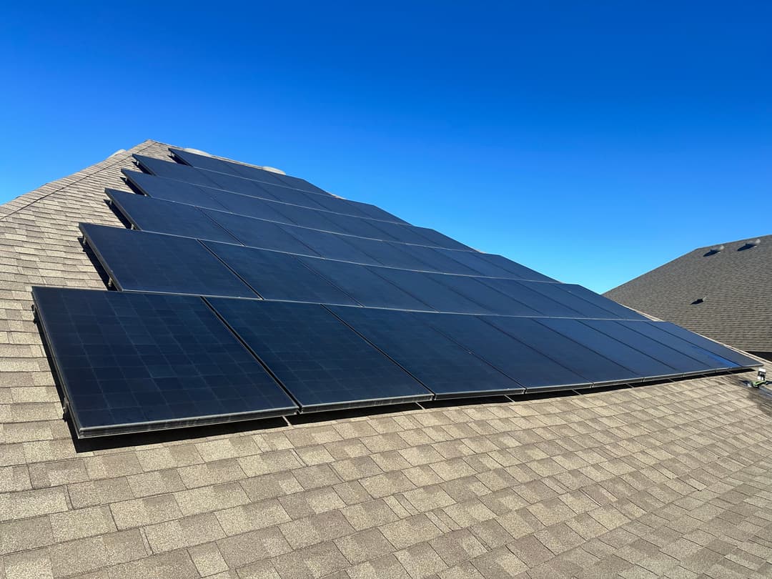 Solar panels installed on a residential roof under a clear blue sky.