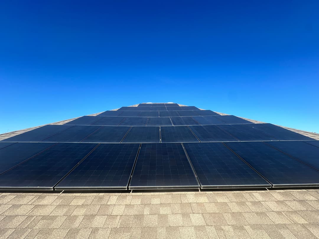 Solar panels installed on a roof under a clear blue sky, promoting renewable energy.