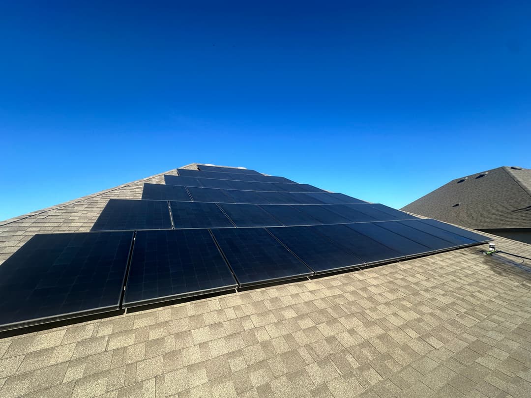 Solar panels on a sloped roof under a clear blue sky, promoting renewable energy.