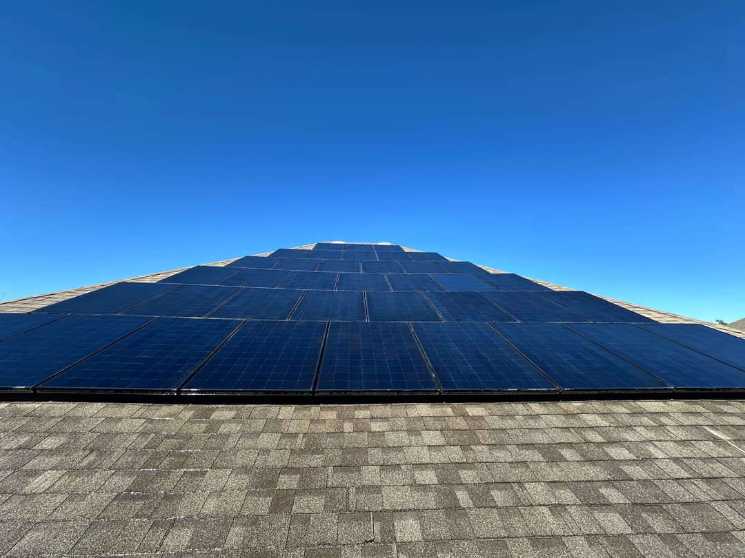 Solar panels installed on a rooftop under a clear blue sky, promoting renewable energy.