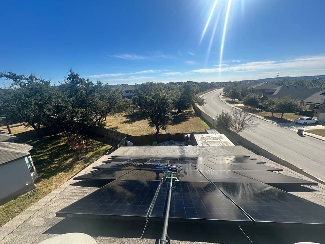 Solar panels installed on a rooftop with a clear blue sky and residential neighborhood view.