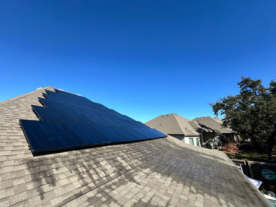 Solar panels on a residential roof under a clear blue sky.