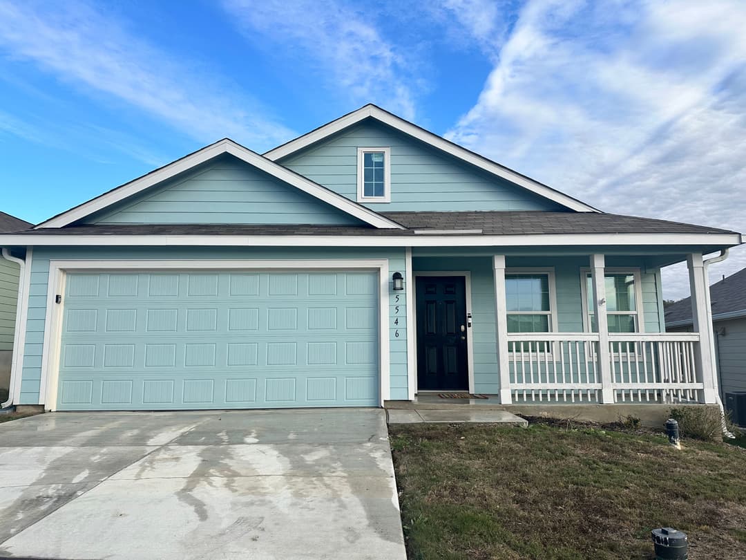 Light blue single-family home with a spacious front porch and garage, located in a residential area.