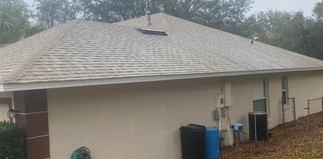 Residential home exterior featuring a sloped shingle roof and utility equipment.
